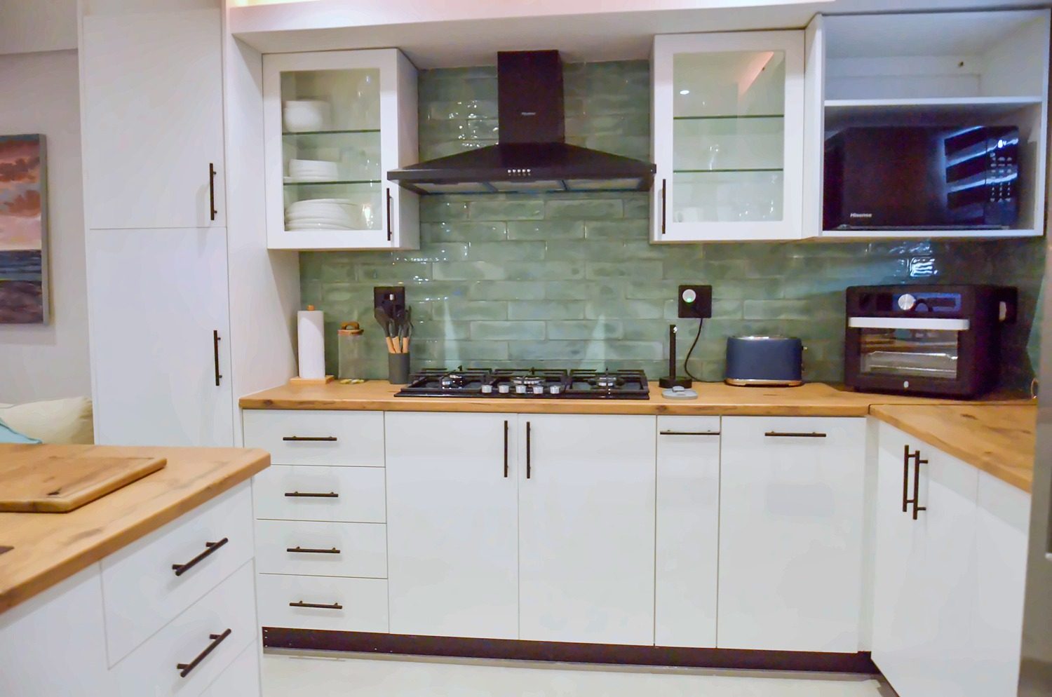 Kitchen with oak worktops, a gas hob and green tiles
