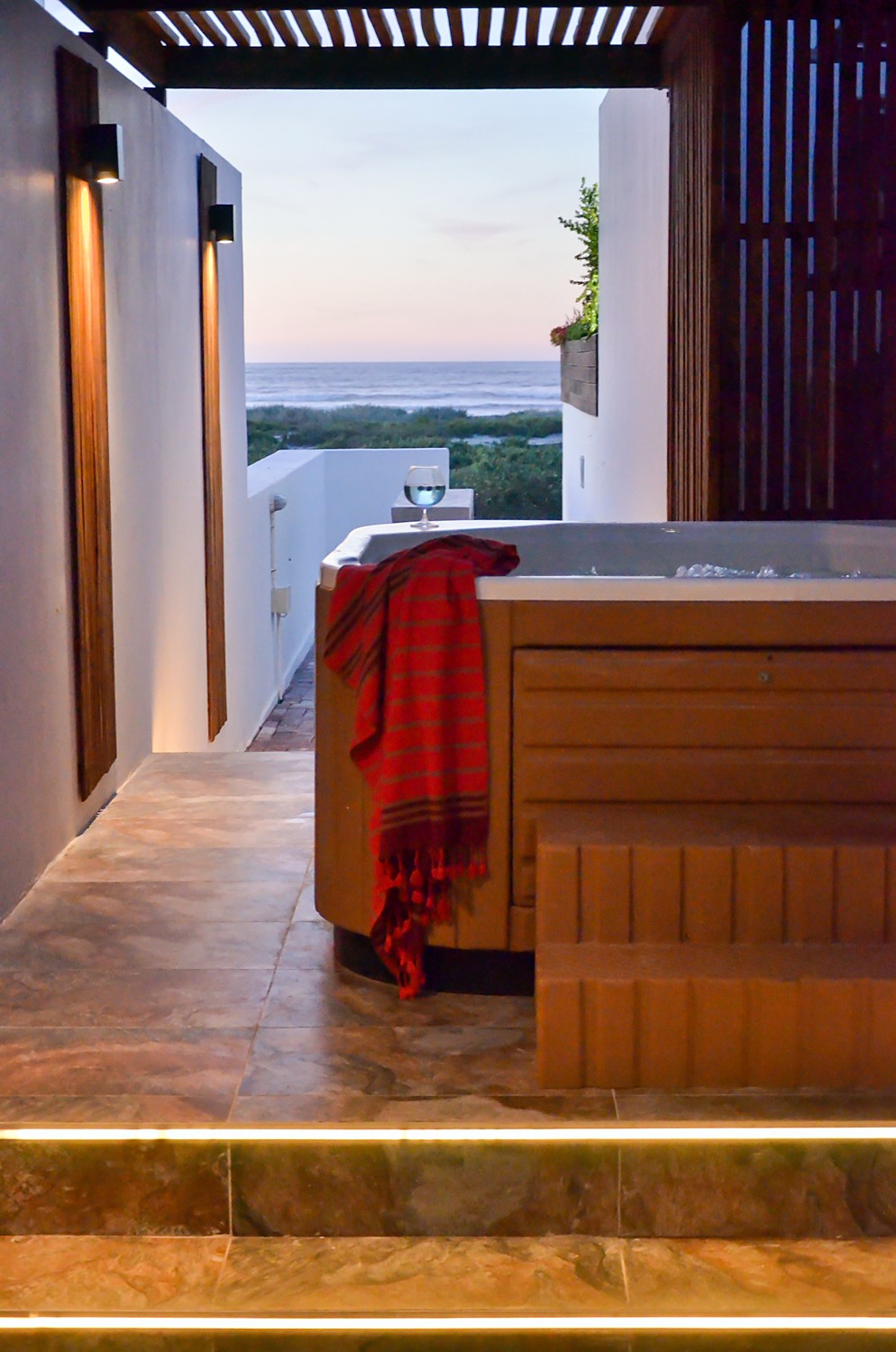 The jacuzzi at dusk with the sea beyond the pergola